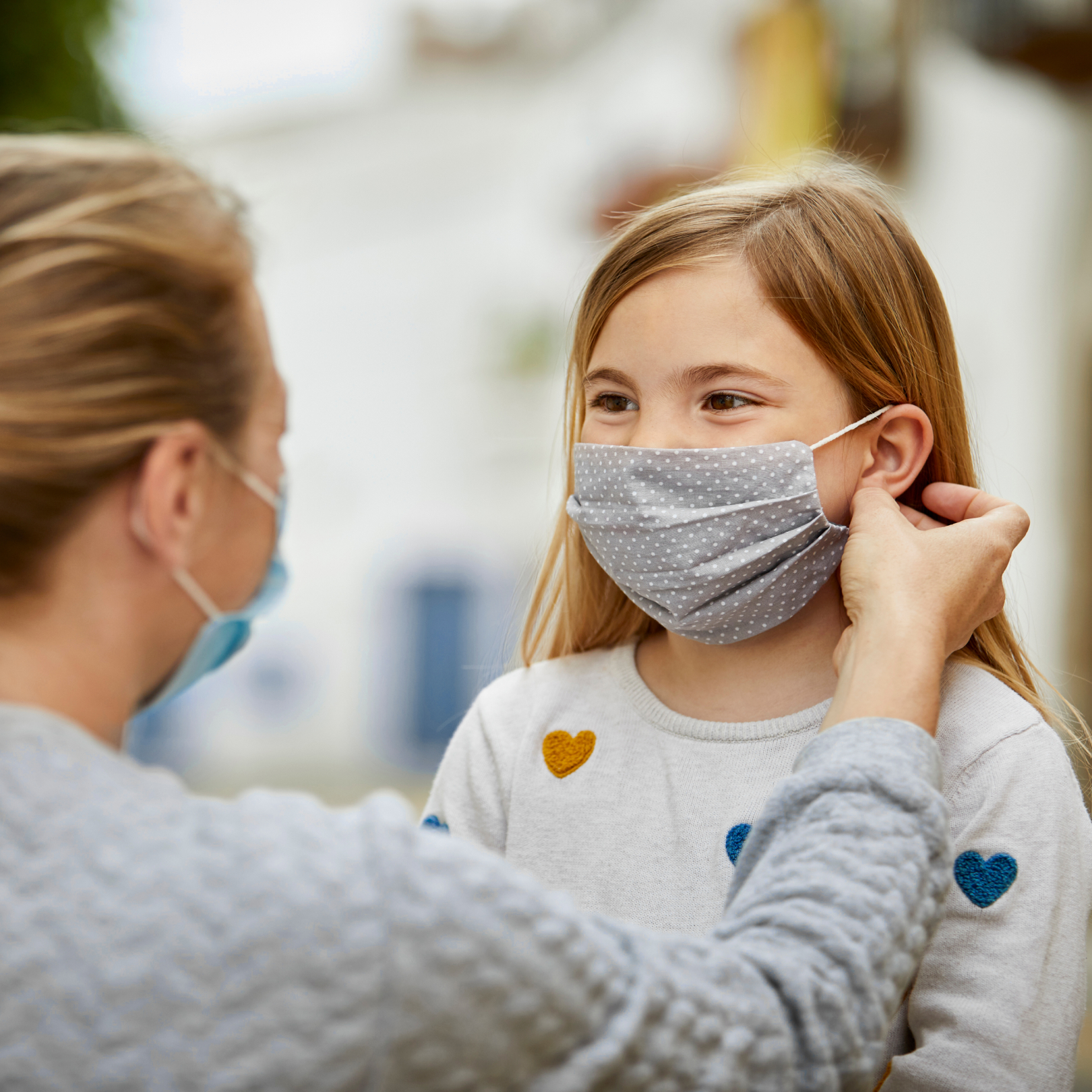 Person helping child put on a mask